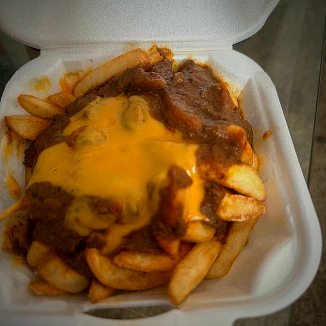 Chili cheese fries with melted American cheese in a takeout container.