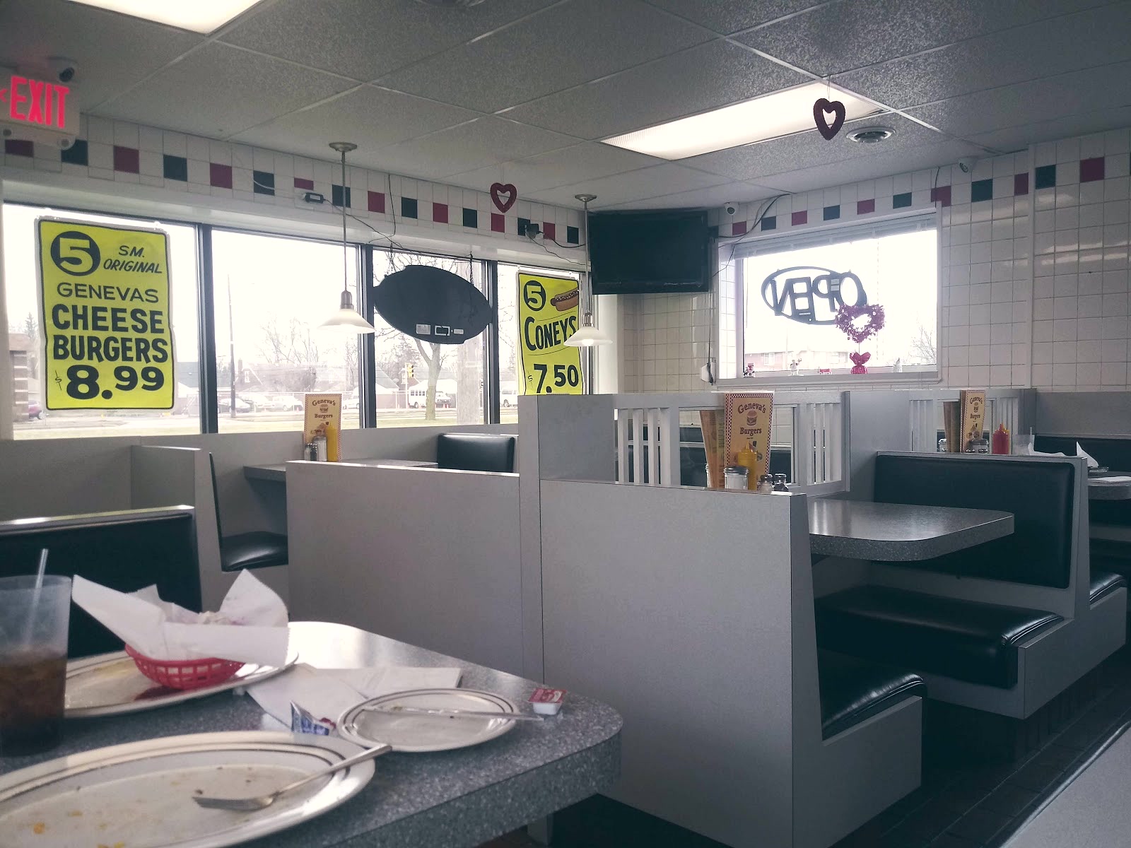 Inside Geneva's, black vinyl booths by the windows with checkered trim along the wall.
