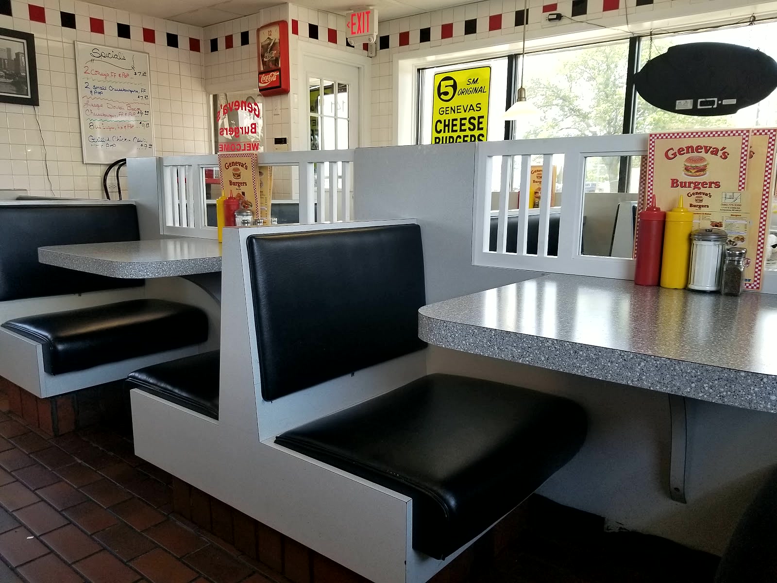 Booths and the window signs inside Geneva's, cheeseburgers and coneys advertised.